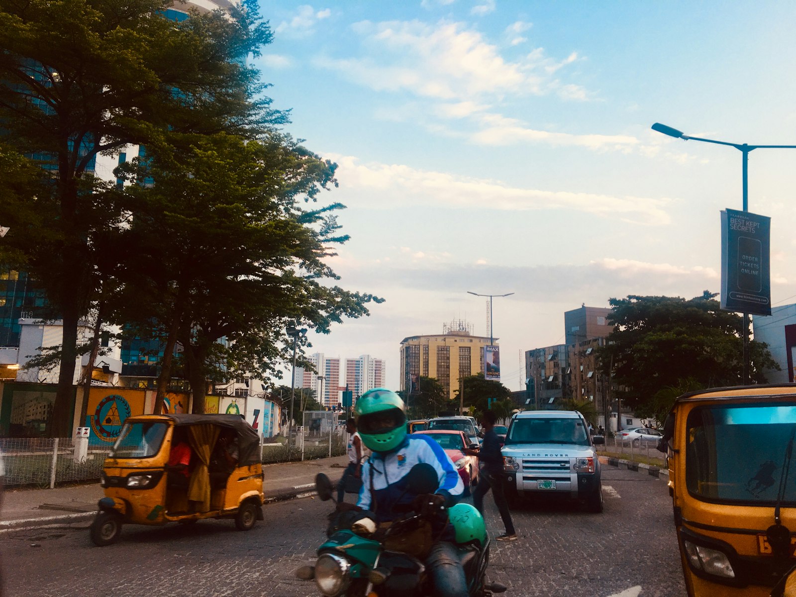 A motorcycle rider in a teal helmet on a Lagos street